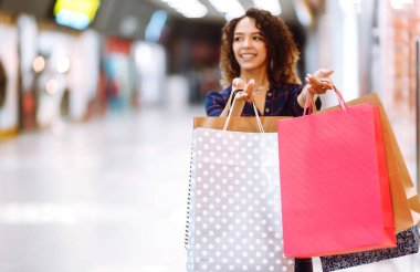 Alışveriş torbaları ellerde. Alışveriş sonrası paketleri olan genç bir kadın. Satın almalar, Kara Cuma, indirimler, satış konsepti.