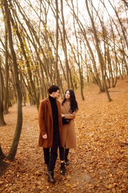 Güzel bir çift sonbahar ormanında birlikte eğleniyor. Moda çifti sonbahar havasının tadını çıkarıyor. Moda, yaşam tarzı ve sonbahar havası.