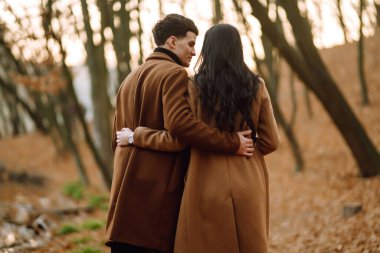 Güzel bir çift sonbahar ormanında birlikte eğleniyor. Moda çifti sonbahar havasının tadını çıkarıyor. Moda, yaşam tarzı ve sonbahar havası.