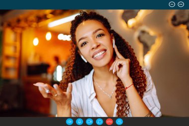 Genç Afrikalı Amerikalı kadının vesikalık portre görüntüsü evde oturup arkadaşlarıyla ya da akrabalarıyla görüntülü konuşma, bilgisayardaki iş kameraları konferansı, kapalı alanda online kurs..