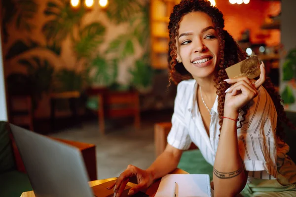 카드를 노트북 컴퓨터를 사용하는 아프리카계 미국인 여성이 인터넷 쇼핑을 카페에 — 스톡 사진