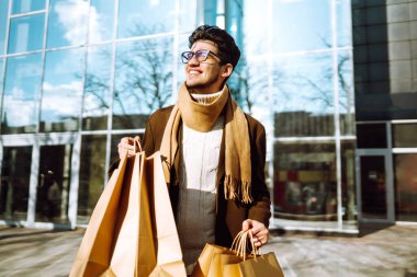 Alışverişten sonra kağıt paketlerle şık bir adam. Alışveriş torbalarıyla gezen genç bir adam. Kara Cuma, satış, tüketici, yaşam tarzı konsepti.