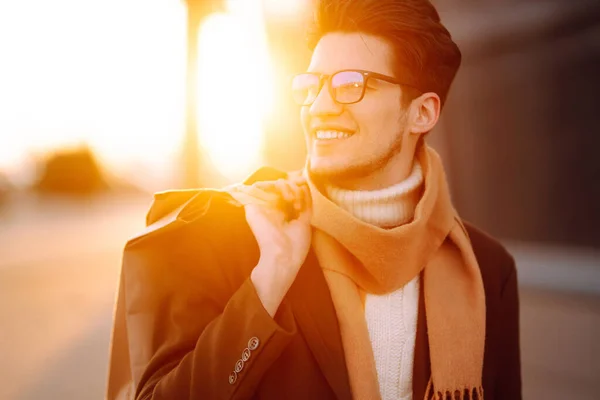 Stylish man with paper packages after shopping at sunset. Handsome man doing shopping in the city. Consumerism, shopping, sales, lifestyle concept. Black friday.