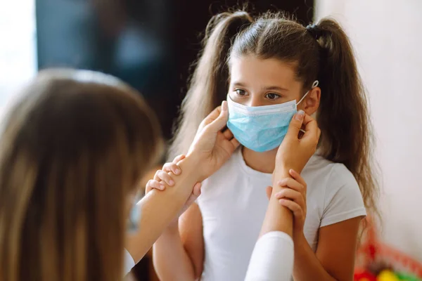 母親は自宅で彼の少女滅菌医療マスクを置きます 母親と娘は感染症やインフルエンザに対する保護マスクを使用しています Covid 19隔離 — ストック写真