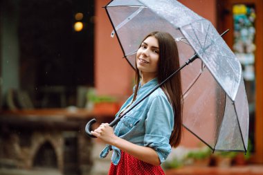 Dışarıda yürürken şemsiyesini tutan neşeli bir kadın. Yağmurlu bir günde sokakta şemsiyeli güzel bir kadın. Sonbahar konsepti.