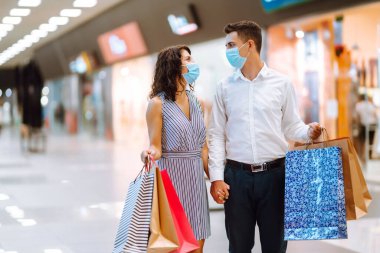 Alışveriş torbaları tutan ve alışveriş merkezinde alışveriş yapan genç ve güzel bir çift. Tüketim, alım, aşk, satış, Kara Cuma konsepti.