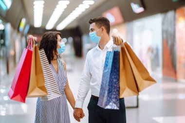 Alışveriş torbaları ellerde. Birlikte alışveriş yapmak. Alışveriş torbaları tutan ve alışveriş merkezinde alışveriş yapan genç bir çift. Tüketim, alım, aşk, satış, Kara Cuma konsepti.