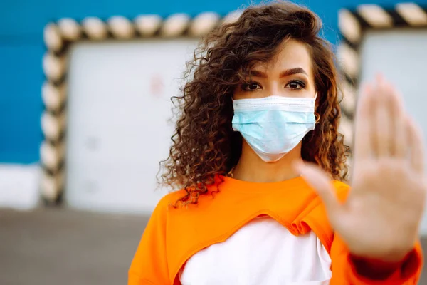 オレンジ色のスーツの路上で保護マスクのかわいい女性 顔マスクを着用 ウイルスの感染から保護します パンデミック 検疫都市での病気の発生と流行 コロナウイルス — ストック写真