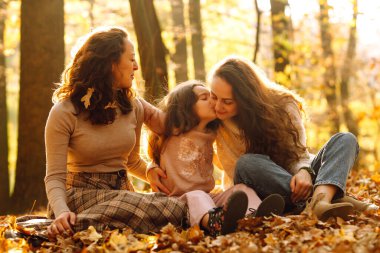 Homoseksüel aile, sonbahar ormanında kızıyla oynuyor. Birlikte olduklarında macera daha eğlenceli oluyor. Sonbahar kadınları.