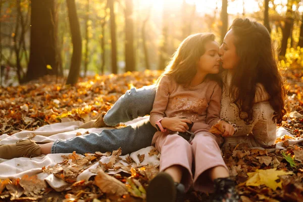 Portrait of happy mother and daughter in autumn forest at sunset.  Young Mother and daughter walking in the autumn park. Autumn women.