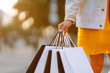 Siyah beyaz alışveriş torbaları taşıyan bir kadının elini yakın çekim. Tüketim, satın alma, alışveriş, yaşam tarzı konsepti.