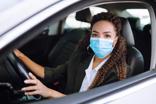 Young woman driving car with protective mask on her face. Transport isolation to stop spread of virus of covid-19. Healthcare concept.