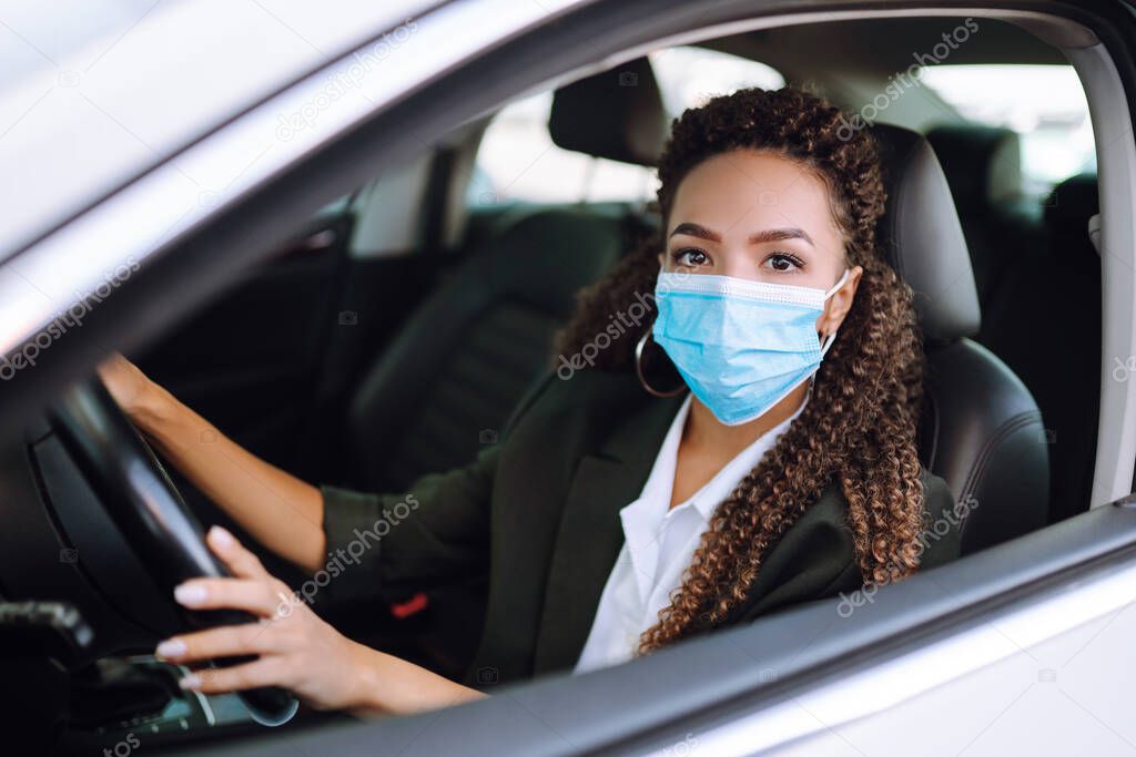 Young woman driving car with protective mask on her face. Transport isolation to stop spread of virus of covid-19. Healthcare concept.