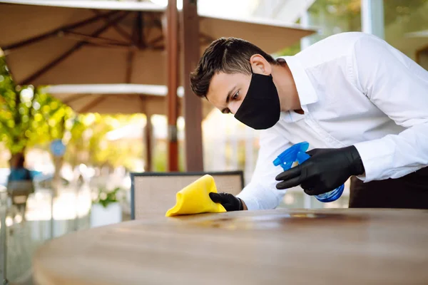 Servitören Bär Skyddande Ansiktsmask Och Handskar När Han Desinficerar Borden — Stockfoto