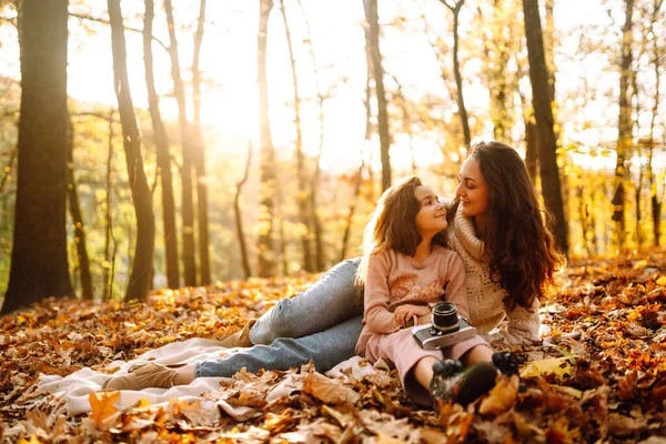 年轻的母亲和女儿在秋天的森林里玩得很开心 日落时 妈妈和孩子拥抱在一起 在秋天的公园休息 — 图库照片