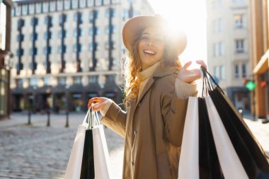 Güneşli bir günde elinde poşet tutan şapkalı gülümseyen bir kadının portresi. Genç bir kadın alışveriş yaptıktan sonra kalabalık bir şehirde dolaşır. İndirim kavramı, hafta sonu.
