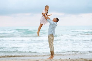 Bir baba ve küçük kızı deniz kıyısında el ele geziyorlar. Mutlu bir adam ve çocuğu dışarıda eğleniyor, birlikte eğleniyorlar. Çocukluk kavramı, rahatlama..