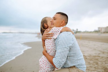 Bir baba ve küçük kızı deniz kıyısında el ele geziyorlar. Mutlu bir adam ve çocuğu dışarıda eğleniyor, birlikte eğleniyorlar. Çocukluk kavramı, rahatlama..