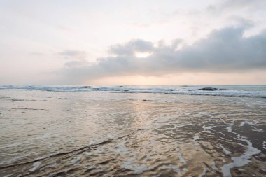 Deniz Burnu. Güneş arka planda batarken kumlu bir sahile yumuşak dalgalar vuruyor. Huzurlu bir manzara. Vahşi yaşam konsepti.