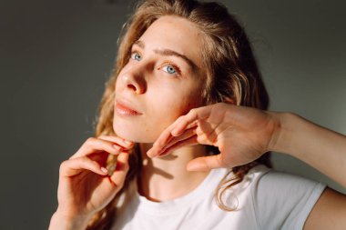 Güneş ışınlarında yüzüne dokunan tatlı bir kadının portresi. Güzel bir kadın rahat bir odada doğal güzellikten hoşlanır. Güzellik, tımar ve doğallık kavramları.