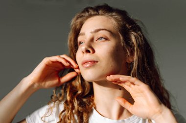 Güneş ışınlarında yüzüne dokunan tatlı bir kadının portresi. Güzel bir kadın rahat bir odada doğal güzellikten hoşlanır. Güzellik, tımar ve doğallık kavramları.