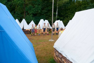 Ormanda kamp, izci üniforması giyen insanlar. 