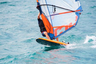 Adam denizde sörf yapıyor, su sporu yapıyor. 