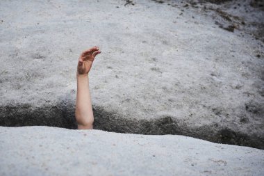 child in asphalt road hole showing hand 