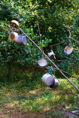 Ağaç dallarında asılı metalik tencereler 