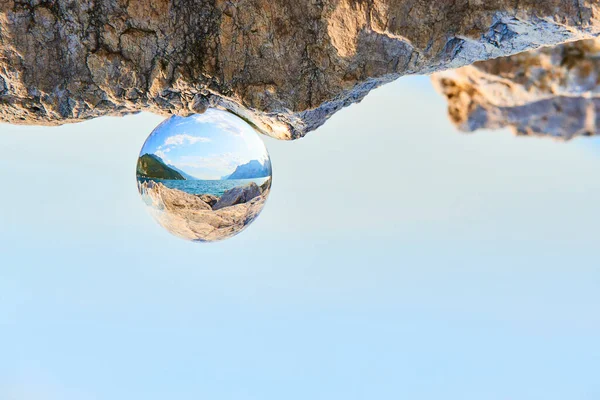 upside down image, clear glass ball on rock landscape