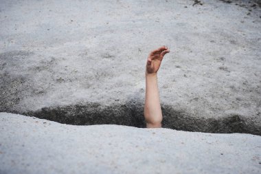 hand of child in asphalt road hole  