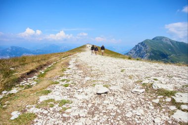 group of people hiking in mountains hills sky with clouds 