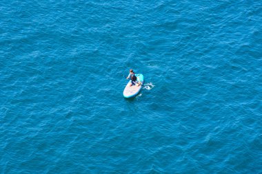 top view of woman on sup board in blue sea water 