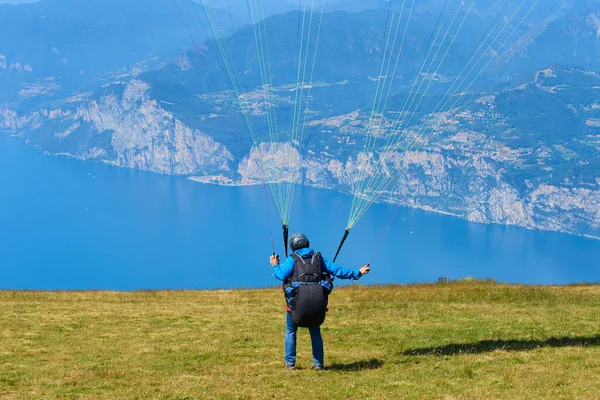 parachutist man getting ready to fly, mountains and lake