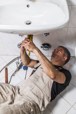 specialist male plumber repairs faucet in bathroom clipart