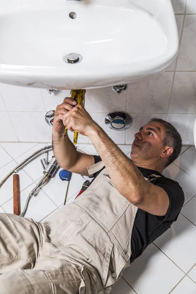 Specialist male plumber repairs faucet in bathroom — Stock Photo, Image