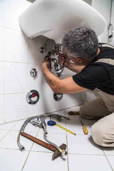 Специалист-сантехник ремонтирует кран в ванной комнате — стоковое фото
