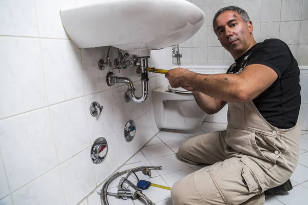 specialist male plumber repairs faucet in bathroom