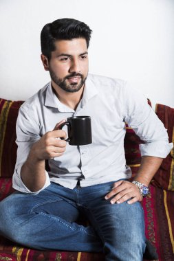 Kanepe ve içecek fincan kahve gülümseyen adam otur