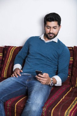 Gülümseyen adam akıllı telefon ile rahat oturuyor