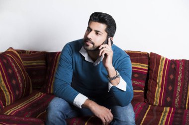 Gülümseyen adam akıllı telefon ile rahat oturuyor