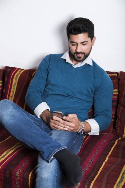 Gülümseyen adam akıllı telefon ile rahat oturuyor