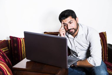 Adam rahat kıyafetler kırık bilgisayarın yakınında oturmak.