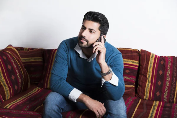 Gülümseyen adam akıllı telefon ile rahat oturuyor