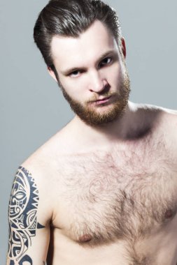 Acımasız kaslı seksi Mürekkeplenmiş kıllı tıraşsız genç adam dövme omuz ve sakal ile