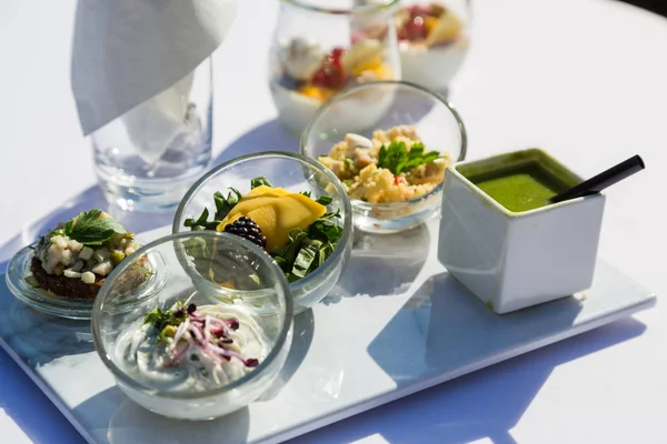 Collation aux légumes, au poisson et à la viande en verre sur table — Photo