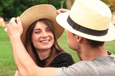 Genç çift oturup birlikte hasır şapka giymiş yerleştirmek
