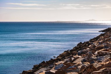 Kayalık sahil ve sakin mavi deniz gökyüzü altında
