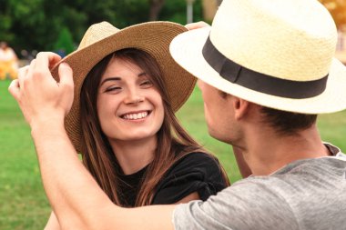 Genç çift oturup birlikte hasır şapka giymiş yerleştirmek