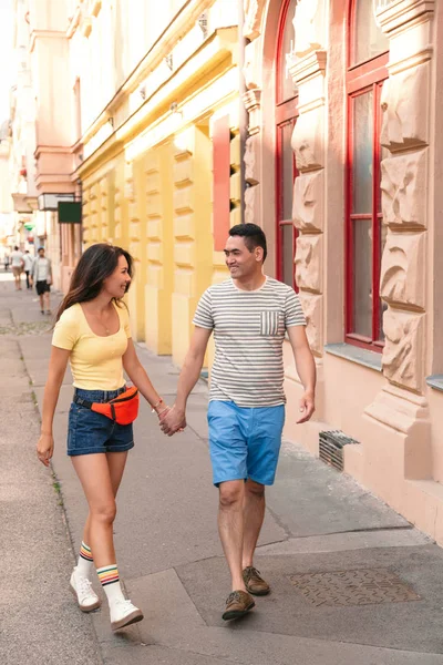 Junges Paar hält Händchen und geht die Straße entlang — Stockfoto